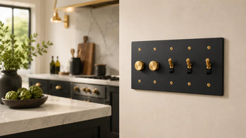 Luxury kitchen featuring a black multi-gang light switch plate with brass dimmer knobs and toggle switches mounted beside dark cabinetry and marble countertops.