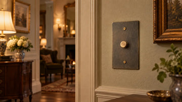 Bronze rotary dimmer switch installed on a cream wall in a traditional home interior