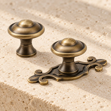 Antique brass domed cabinet knobs with and without ornate backplate on limestone