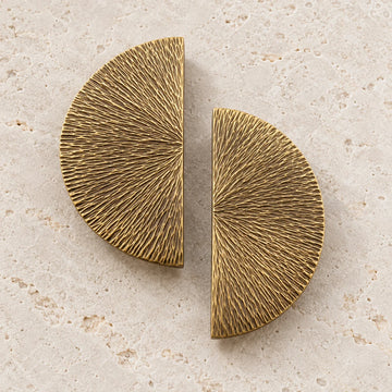 Antique brass half-moon cabinet pulls arranged on limestone; two pieces shown