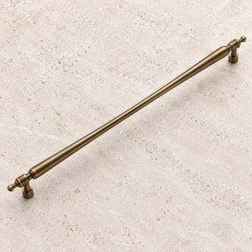 Antique brass long tapered cabinet pull on pale limestone