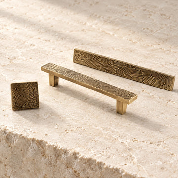 Antique brass textured cabinet pulls and square knob on limestone