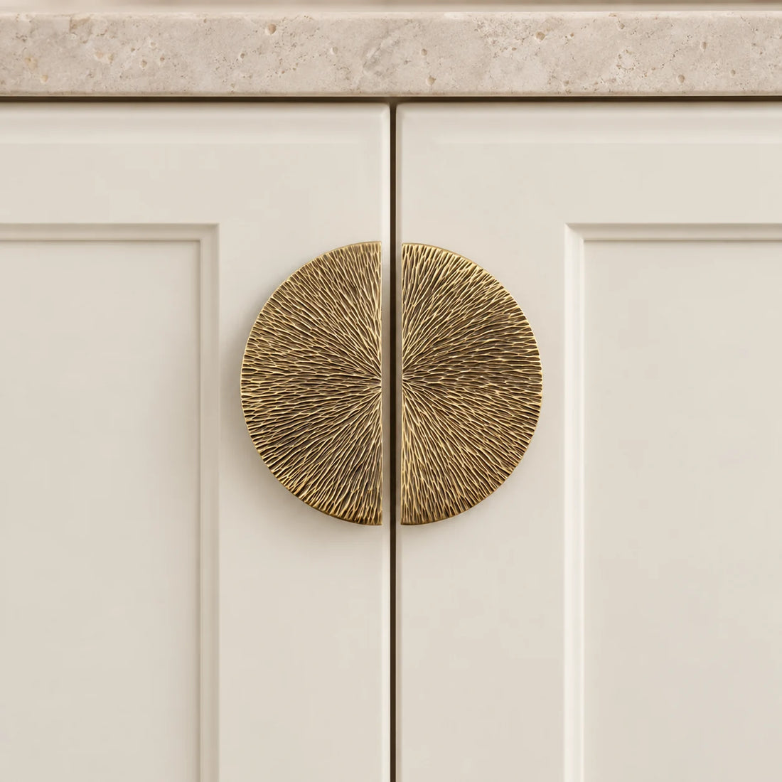 Antique brass half-moon cabinet pulls arranged on limestone; two pieces shown