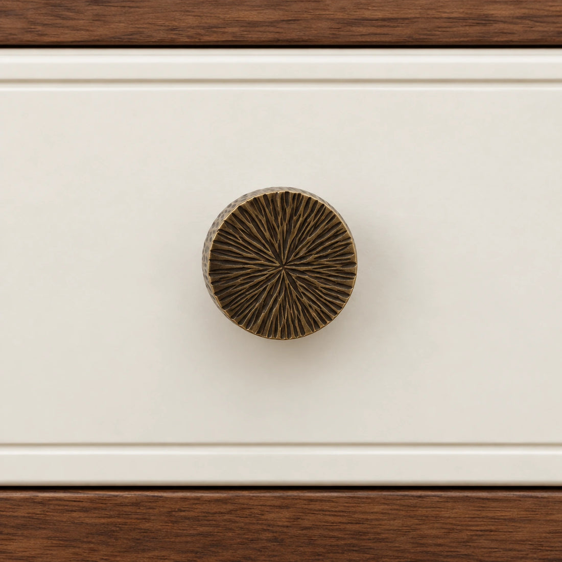 Antique brass radial-textured cabinet knobs arranged on natural limestone