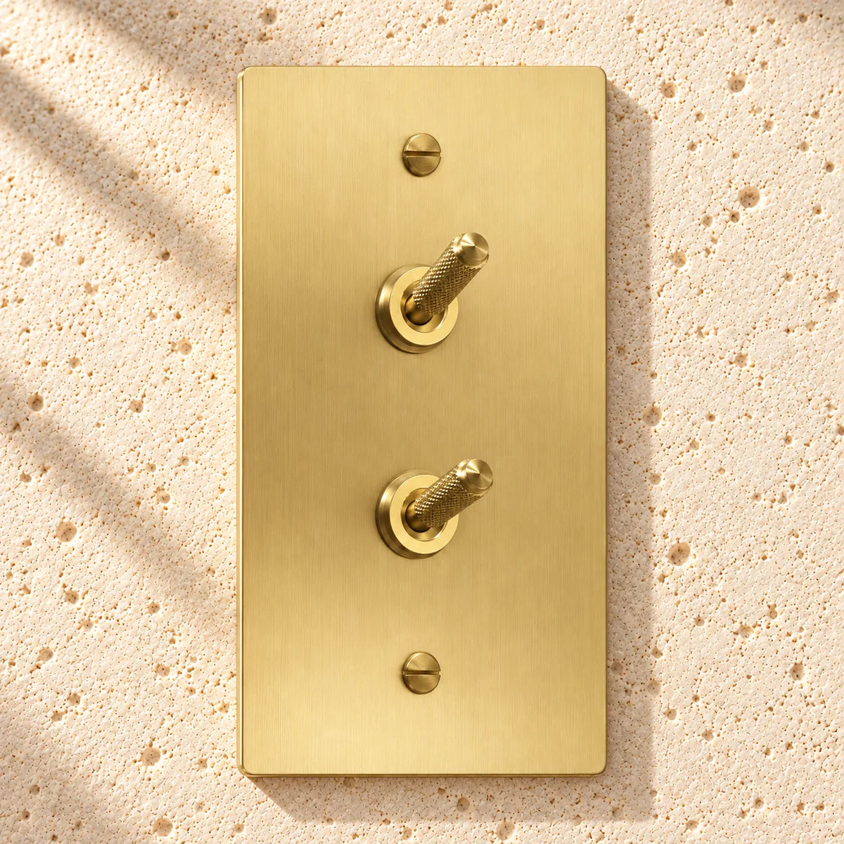 1-Gang Solid Brass Double Knurled Toggle Light Switches on sunlit pale limestone