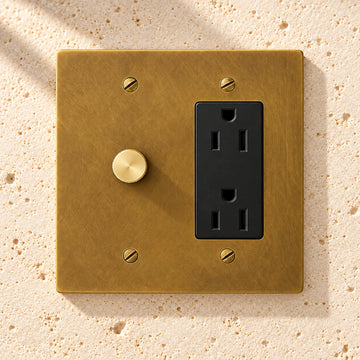 2-Gang Solid Brass Rotary Dimmer + Outlet Combo (Duplex/USB/GFCI) on sunlit pale limestone