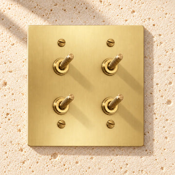 2-Gang Solid Brass Double Knurled Toggle Light Switches on sunlit pale limestone