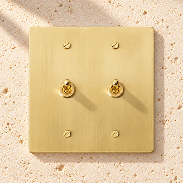 2-Gang Solid Brass Retro Toggle Light Switch on sunlit pale limestone