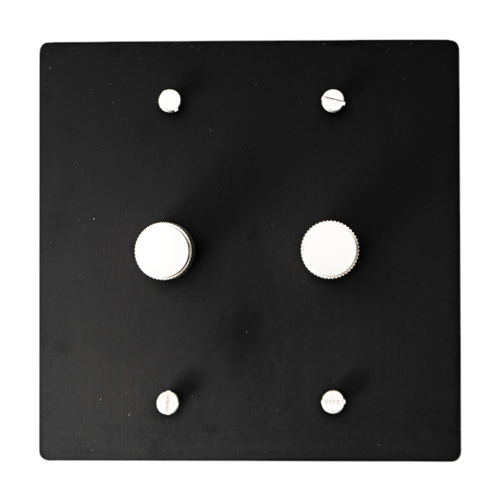 Black square wall plate with silver knobs and screws on a white background