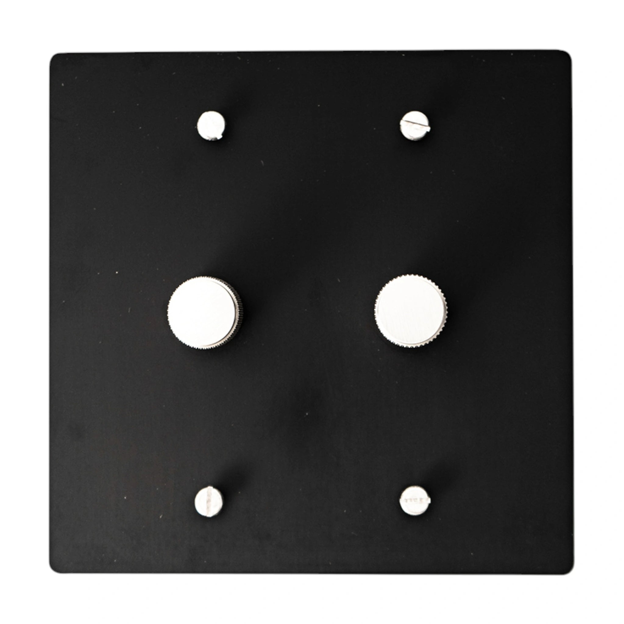 Black square wall plate with silver knobs and screws on a white background