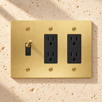 3-Gang Knurled Brass Toggle Light Switch & 2 Duplex Outlets on sunlit pale limestone