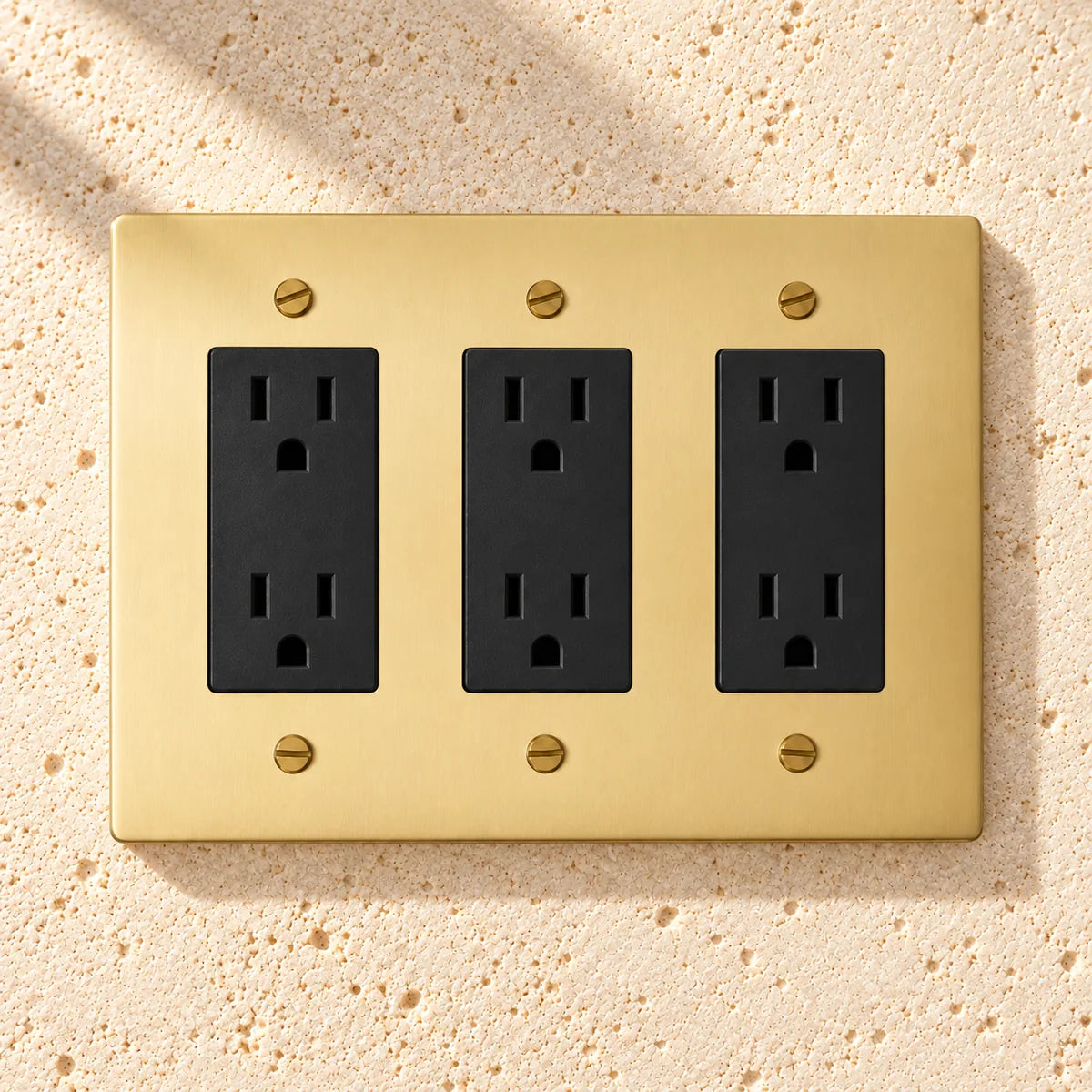 3-Gang Solid Brass Duplex Outlets — 6 Receptacles on sunlit pale limestone