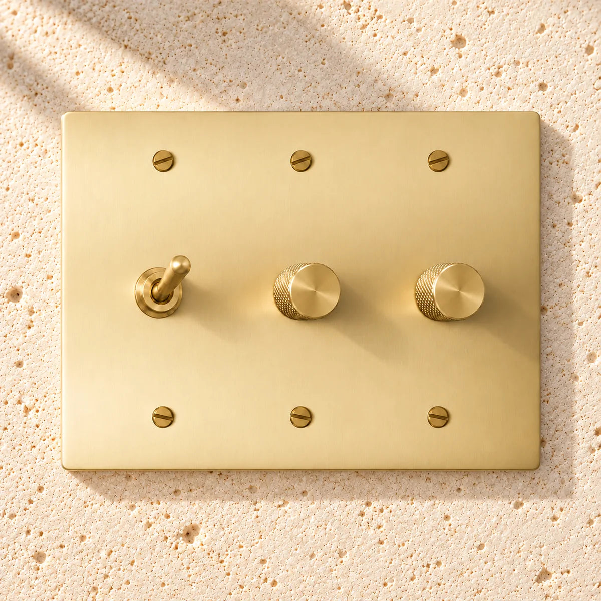3-Gang Solid Brass Toggle Light Switch & 2 Rotary Dimmers on sunlit pale limestone
