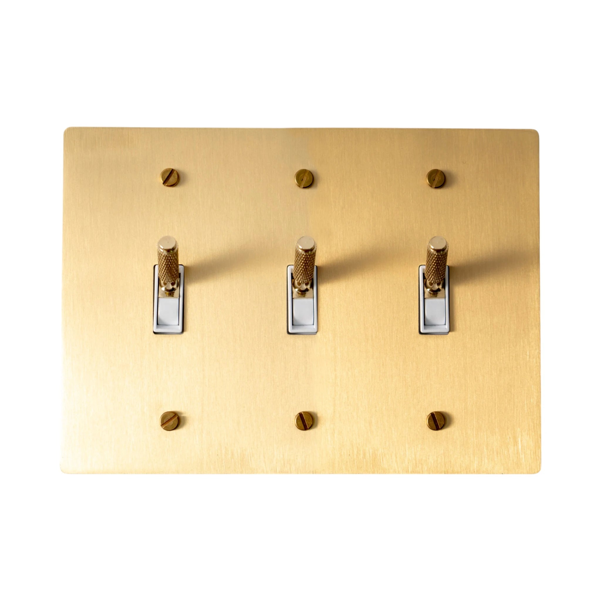 Close-up of knurled toggle levers on satin brass 3-gang switch plate