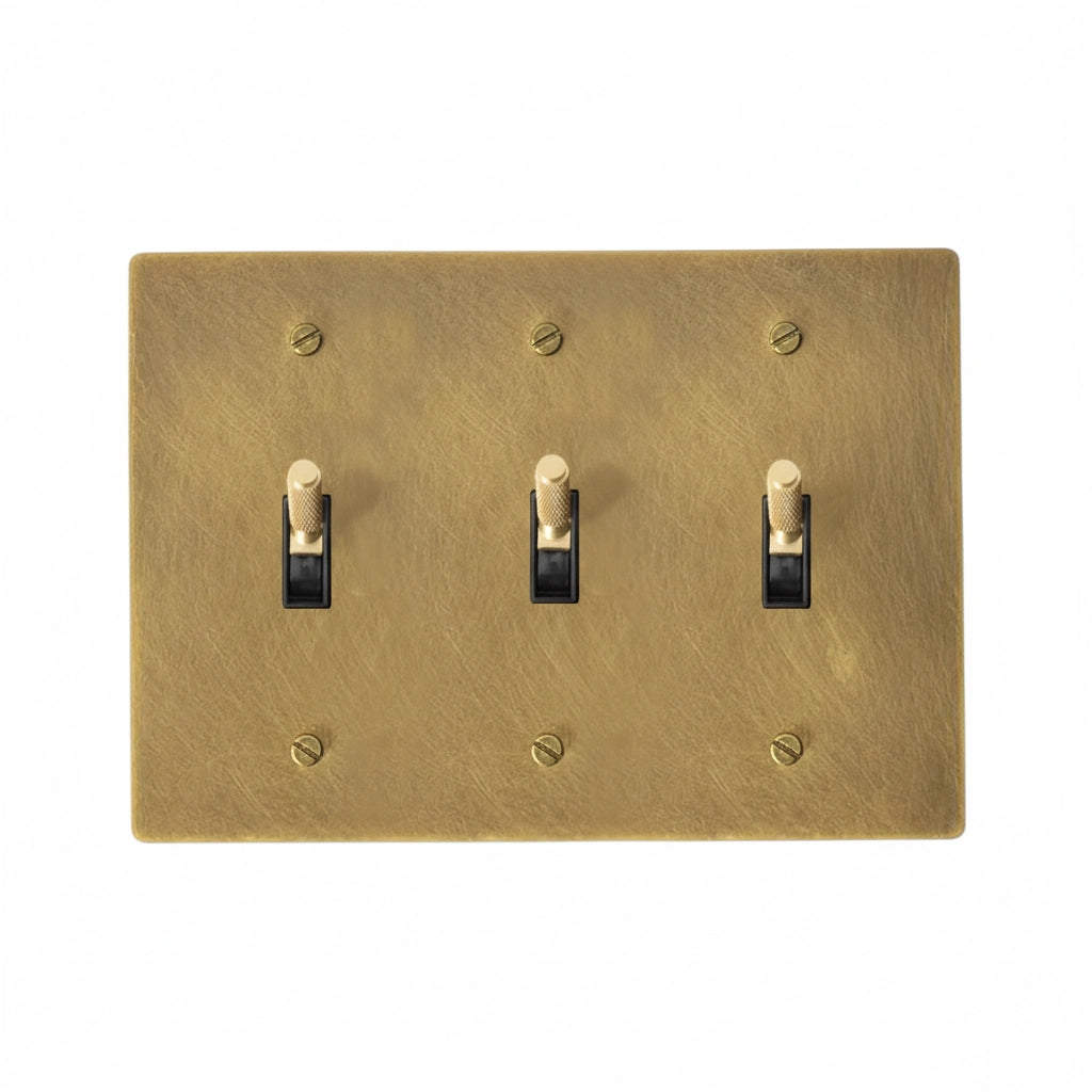 Bronze three-toggle switch plate with brass screws on a white background