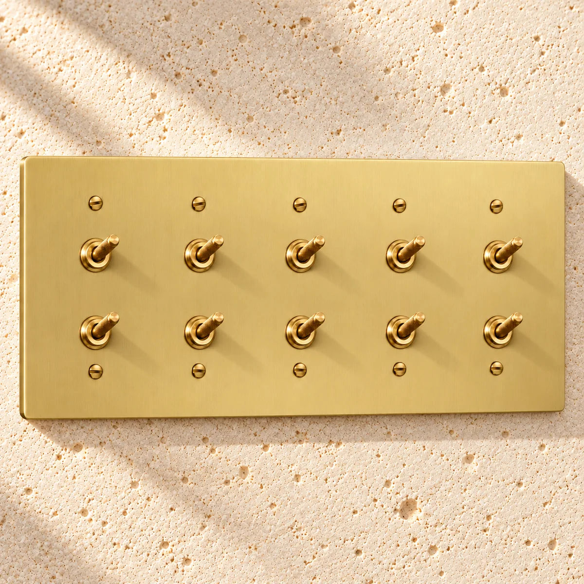 5-Gang Solid Brass Double Knurled Toggle Light Switches on sunlit pale limestone
