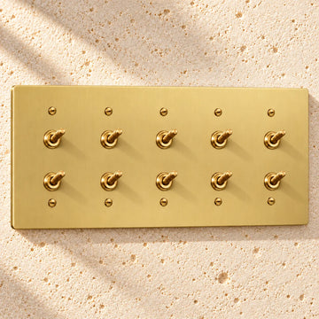 5-Gang Solid Brass Double Knurled Toggle Light Switches on sunlit pale limestone