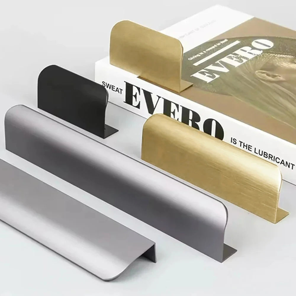 Five aluminium edge pulls in gold, silver, and black on a white surface with a book.