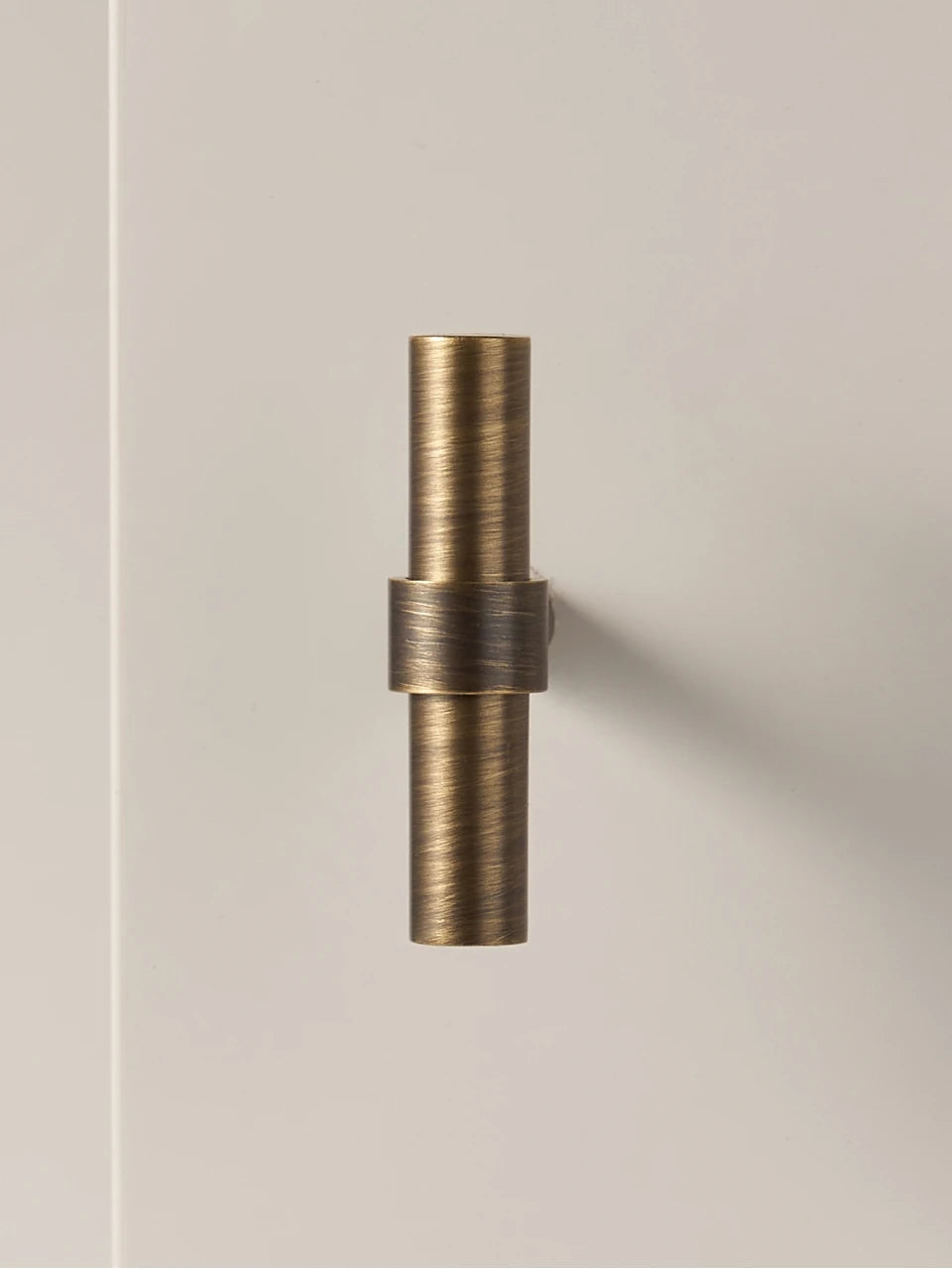 Antique brass stepped ring t-bar on a neutral background.