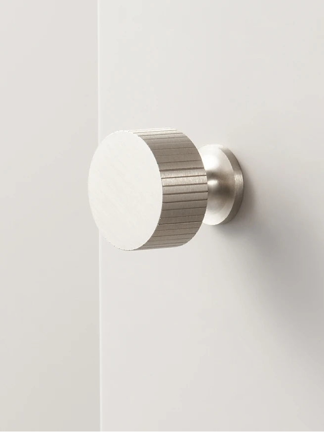 Art deco vertical line door knob on a white door.