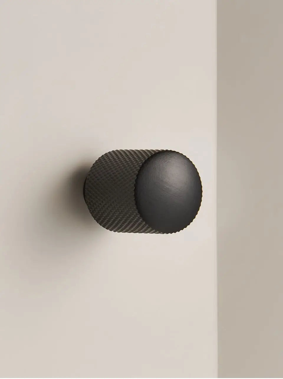 Black cabinet brass cross knurled knob on a neutral background.