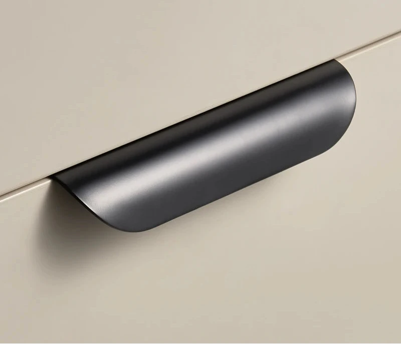 Black cabinet edge pull on a beige surface.
