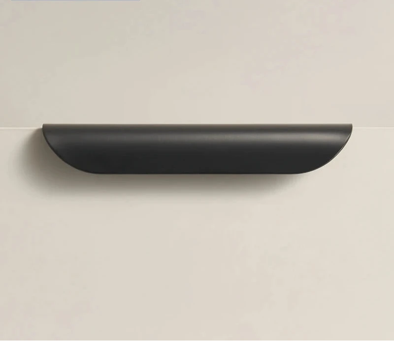 Black cabinet edge pull on a beige surface.