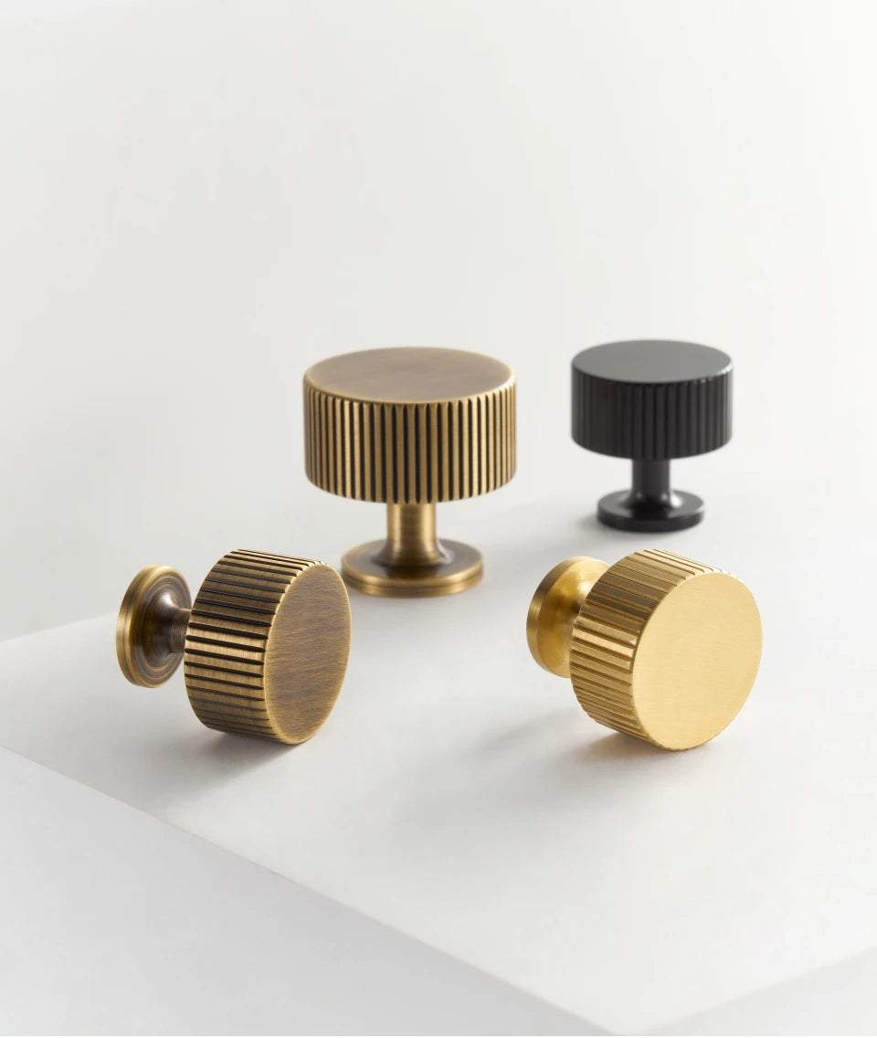 Set of brass, bronze and black art deco cabinet knobs on a white surface.