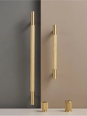 Set of brass cross knurled handles and knobs in a beige and grey background.