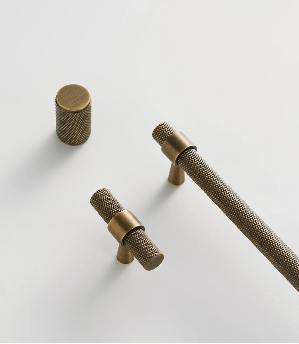 Brass handle, knob and t-bar on a light grey background.