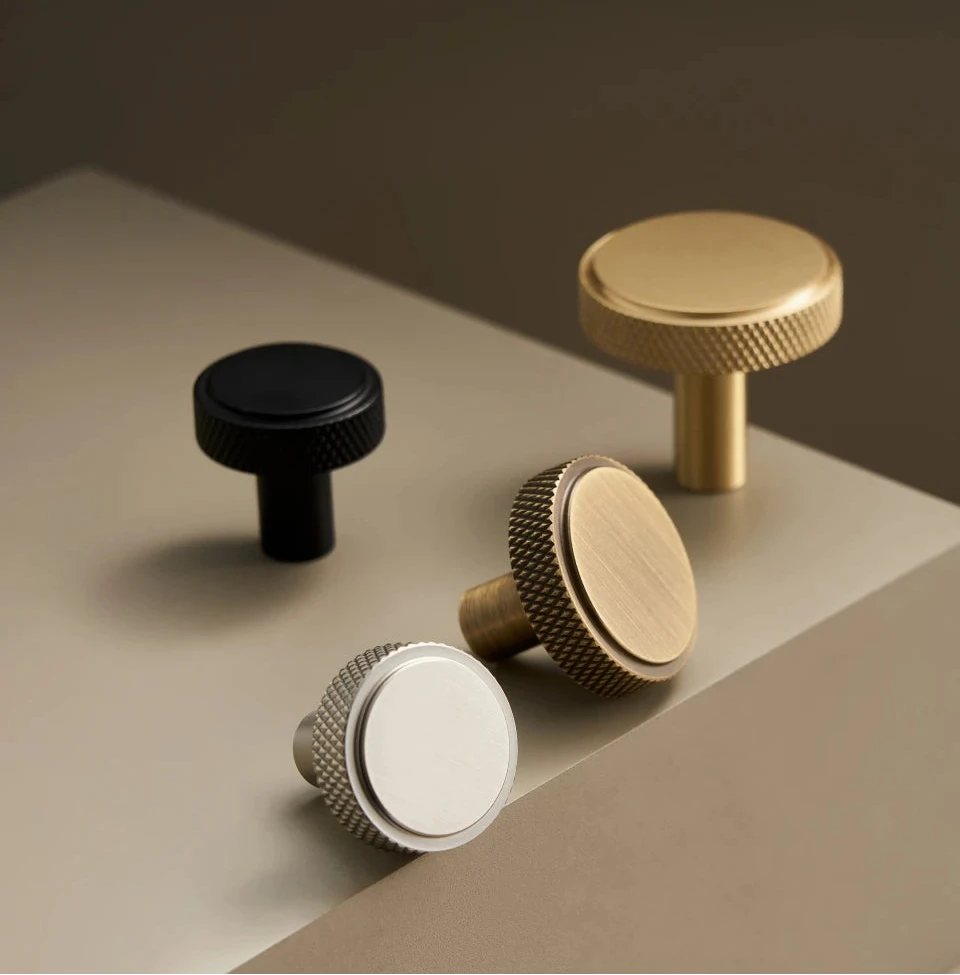 Collection knurled brass knobs on a neutral background.
