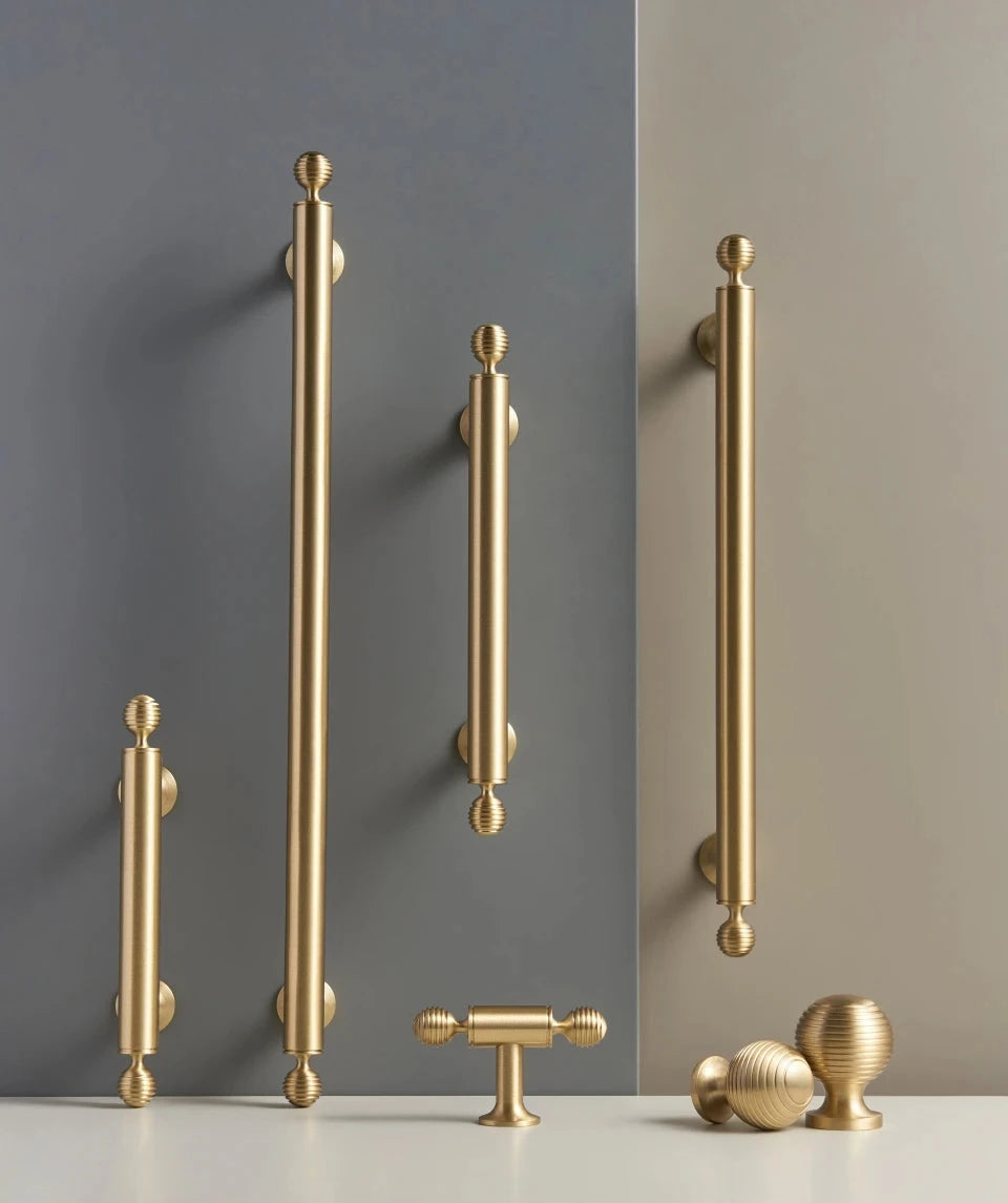 Collection of French luxury brass gold cabinet handles knobs and t-bar on a beige and grey background.