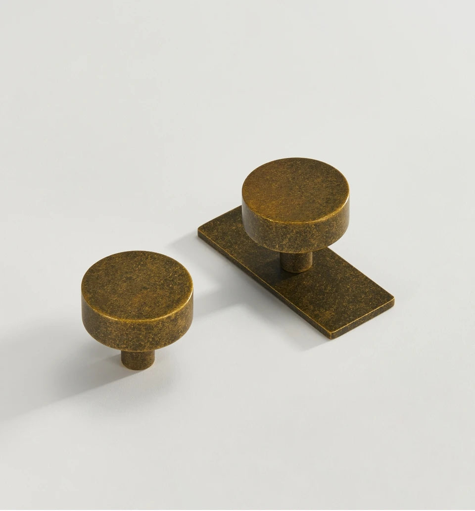 Couple of antique brass ice flower vintage door knobs on a light grey background.