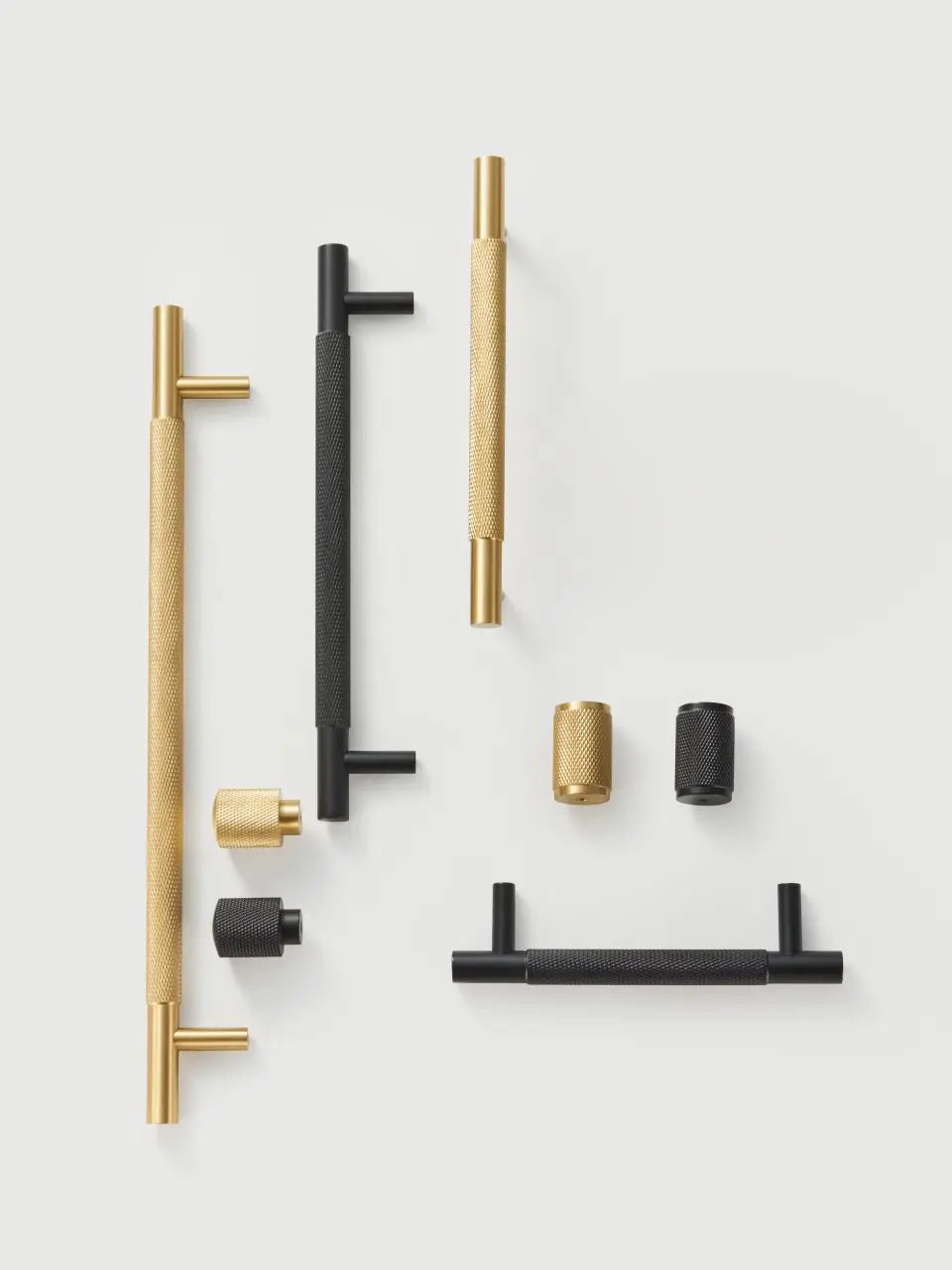 Set of a brass cross knurled gold and black door handles and knobs on a white background.
