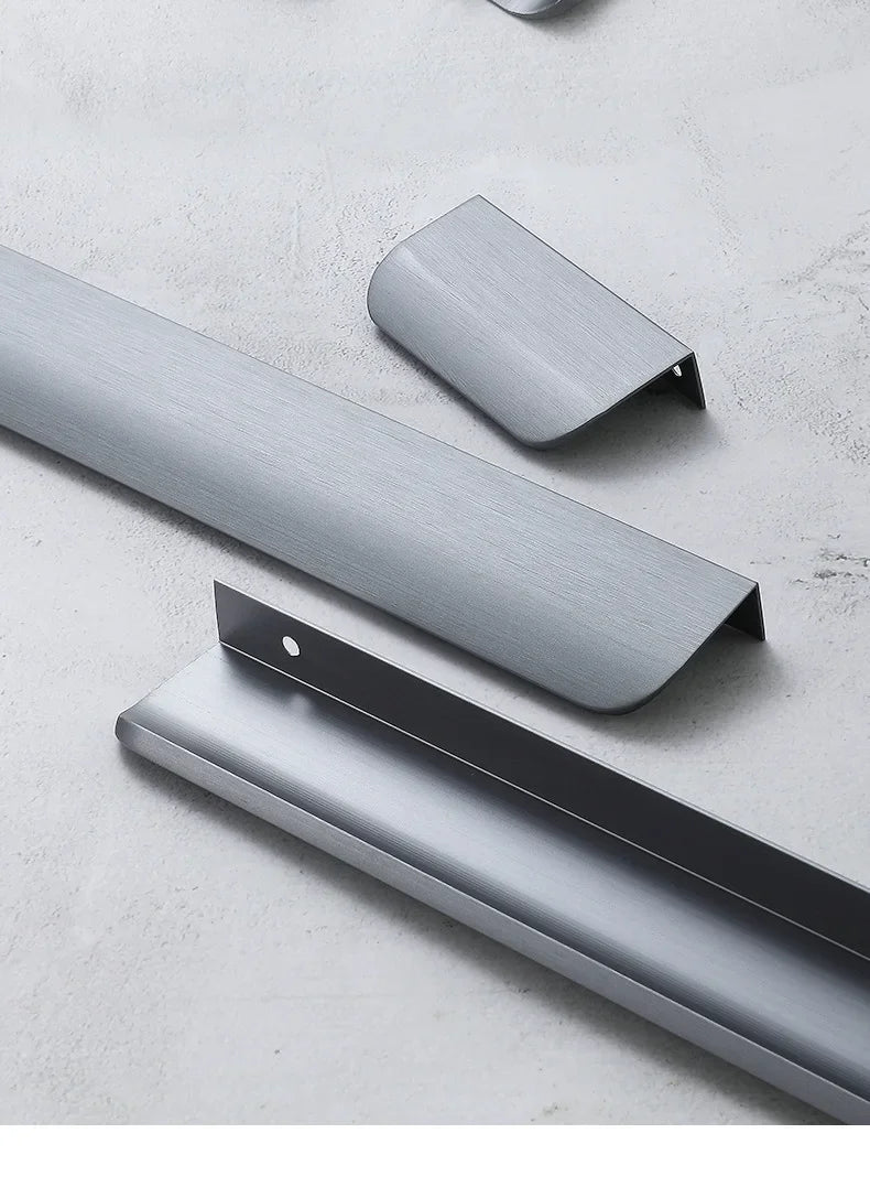 Grey aluminum edge pull handles on a grey concrete surface.