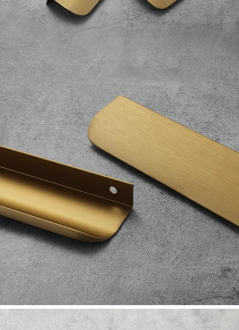 Gold aluminum edge pull handles on a grey concrete surface.