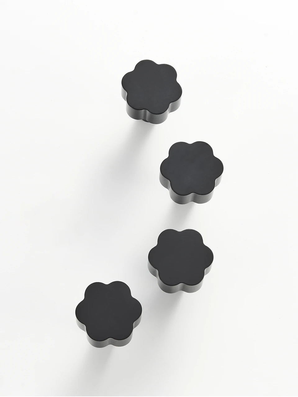 Four black flower cabinet knobs on a white background.