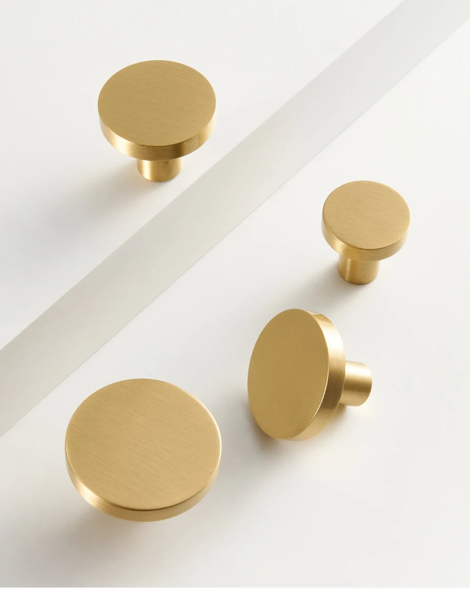Four gold round cabinet knobs on a white background.