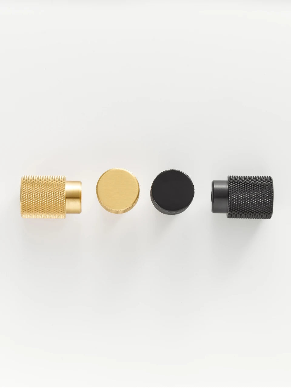 Four knurled brass knobs in gold and black on a white background.