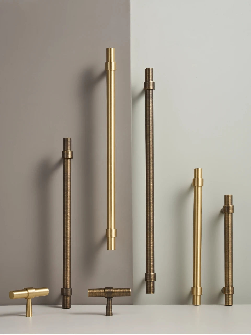 Set of gold and antique brass stepped ring door handles and t-bars on a beige background.