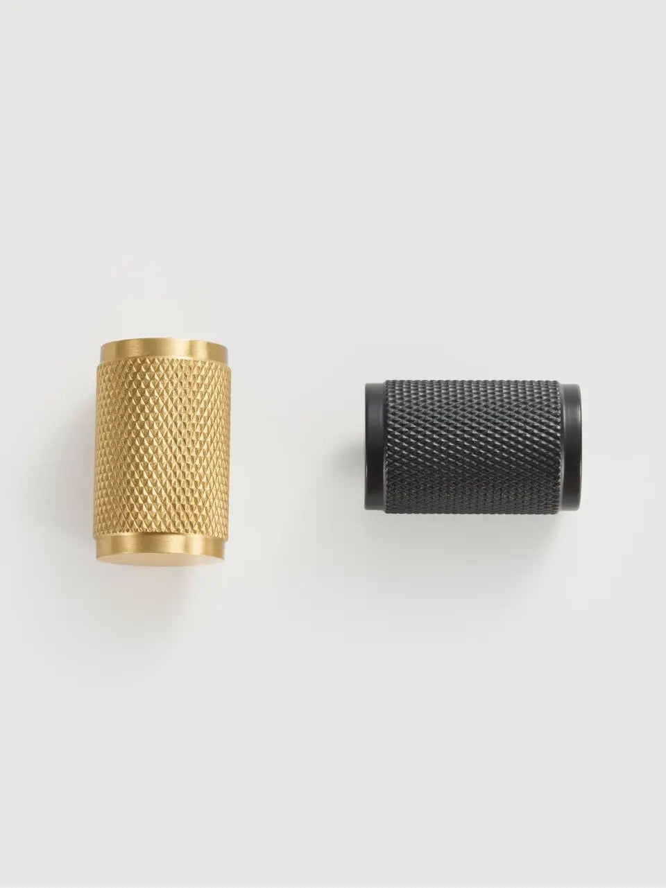 Gold and black brass cross knurled knobs on a light grey background.