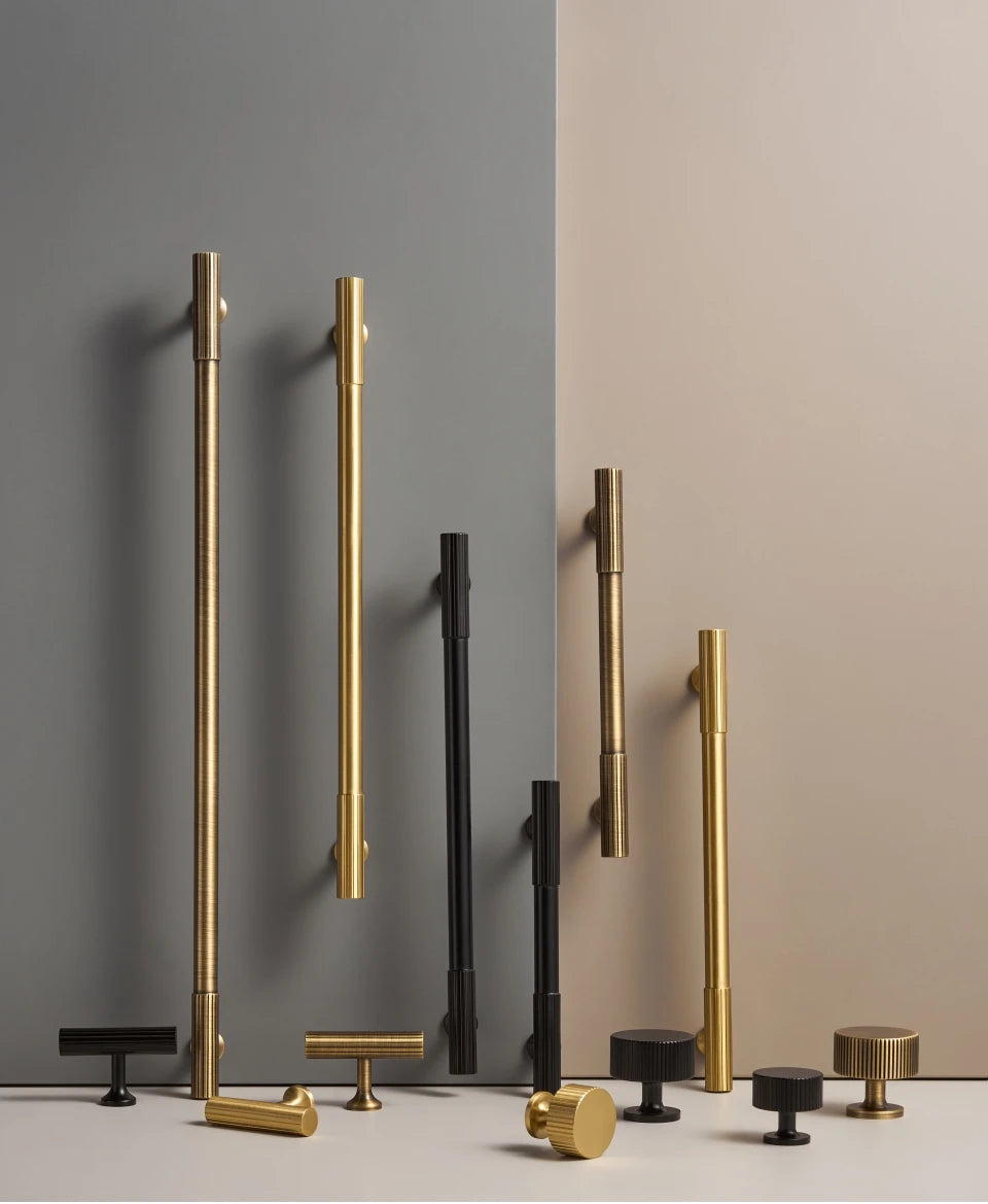 Set of gold, antique and black brass Art Deco pulls, t-bars and knobs on a gray and beige background