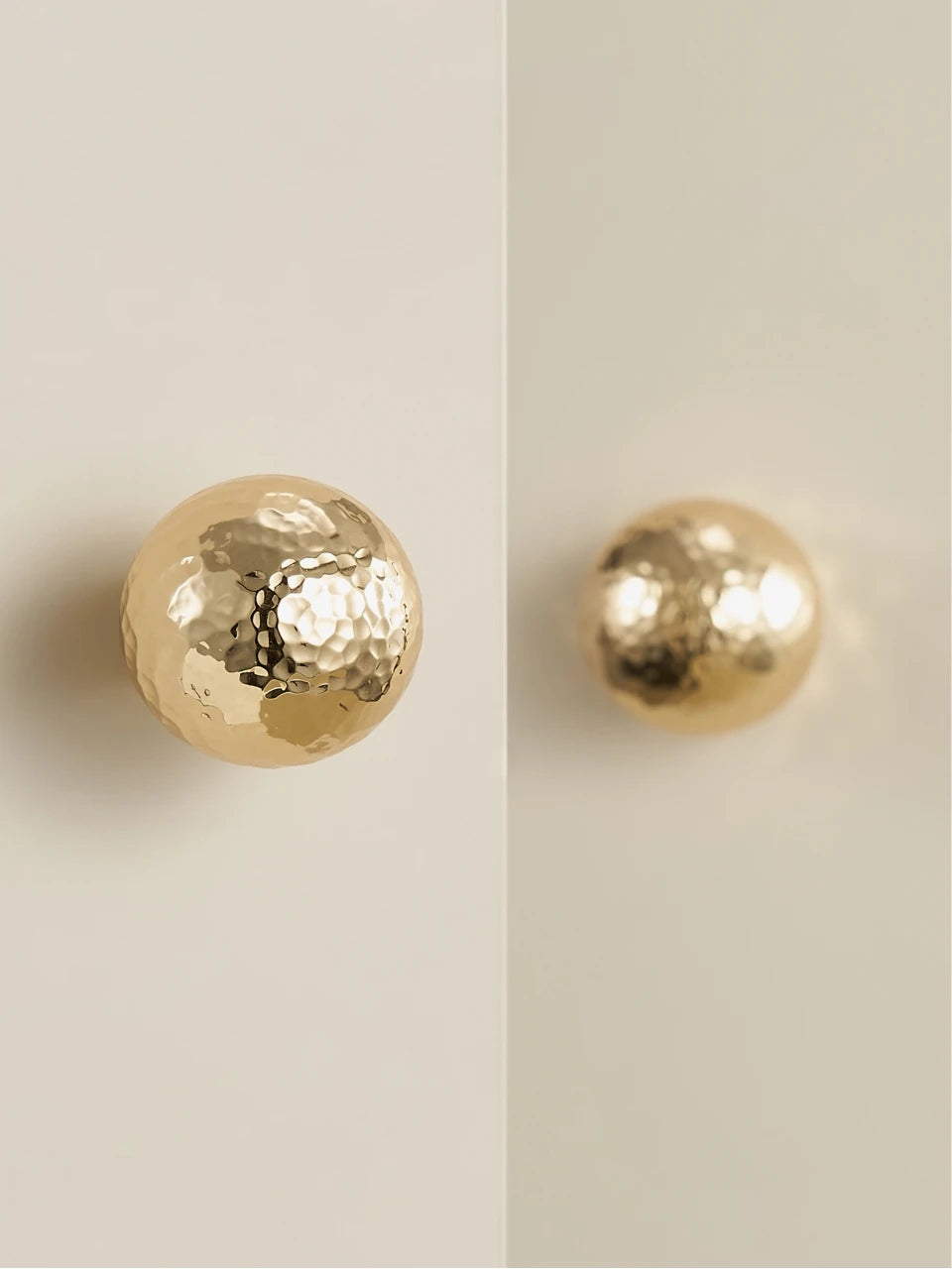 Gold brass hammered ball knobs on a beige cabinet doors.