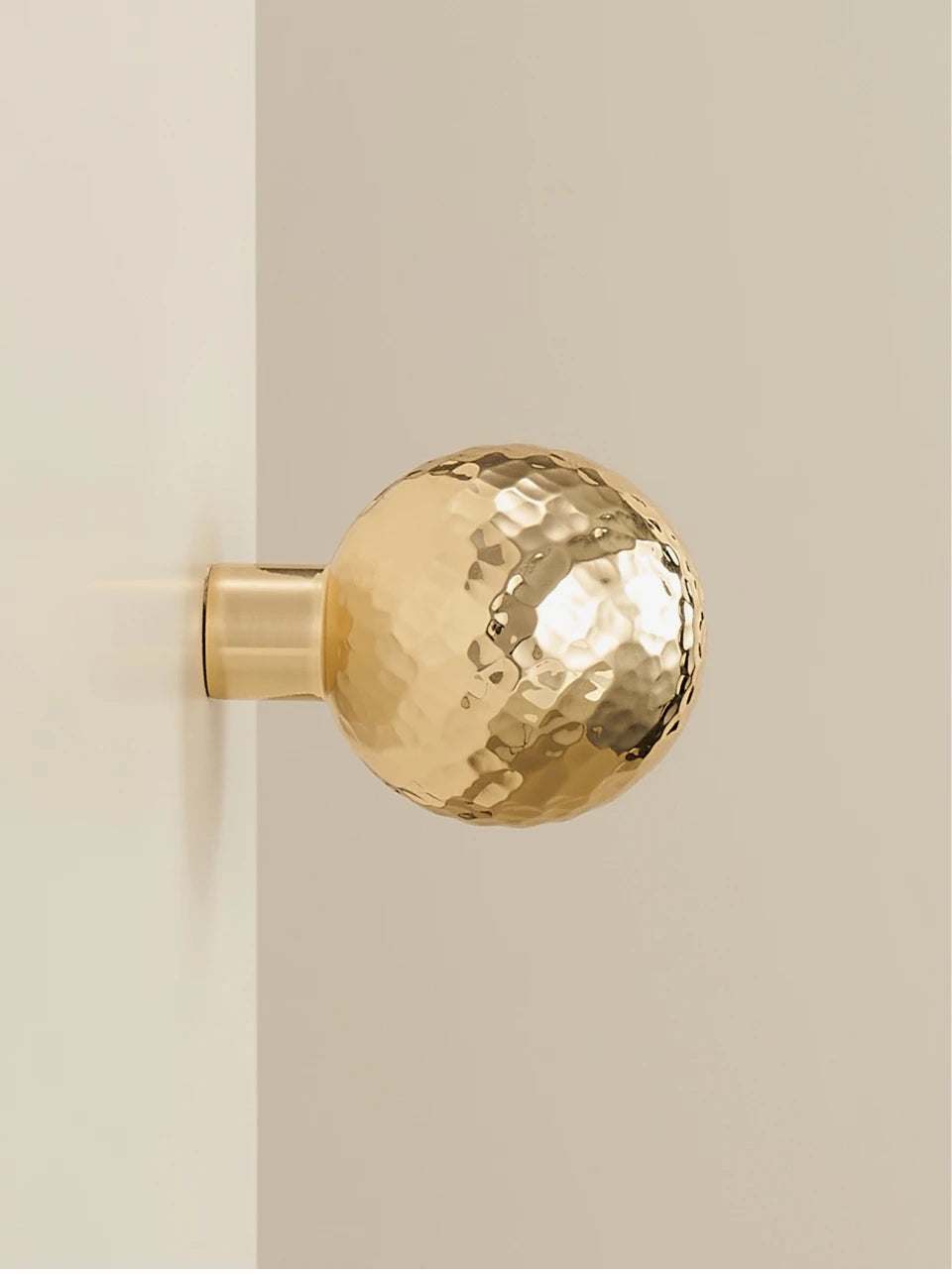 Gold brass hammered knob on a beige background.