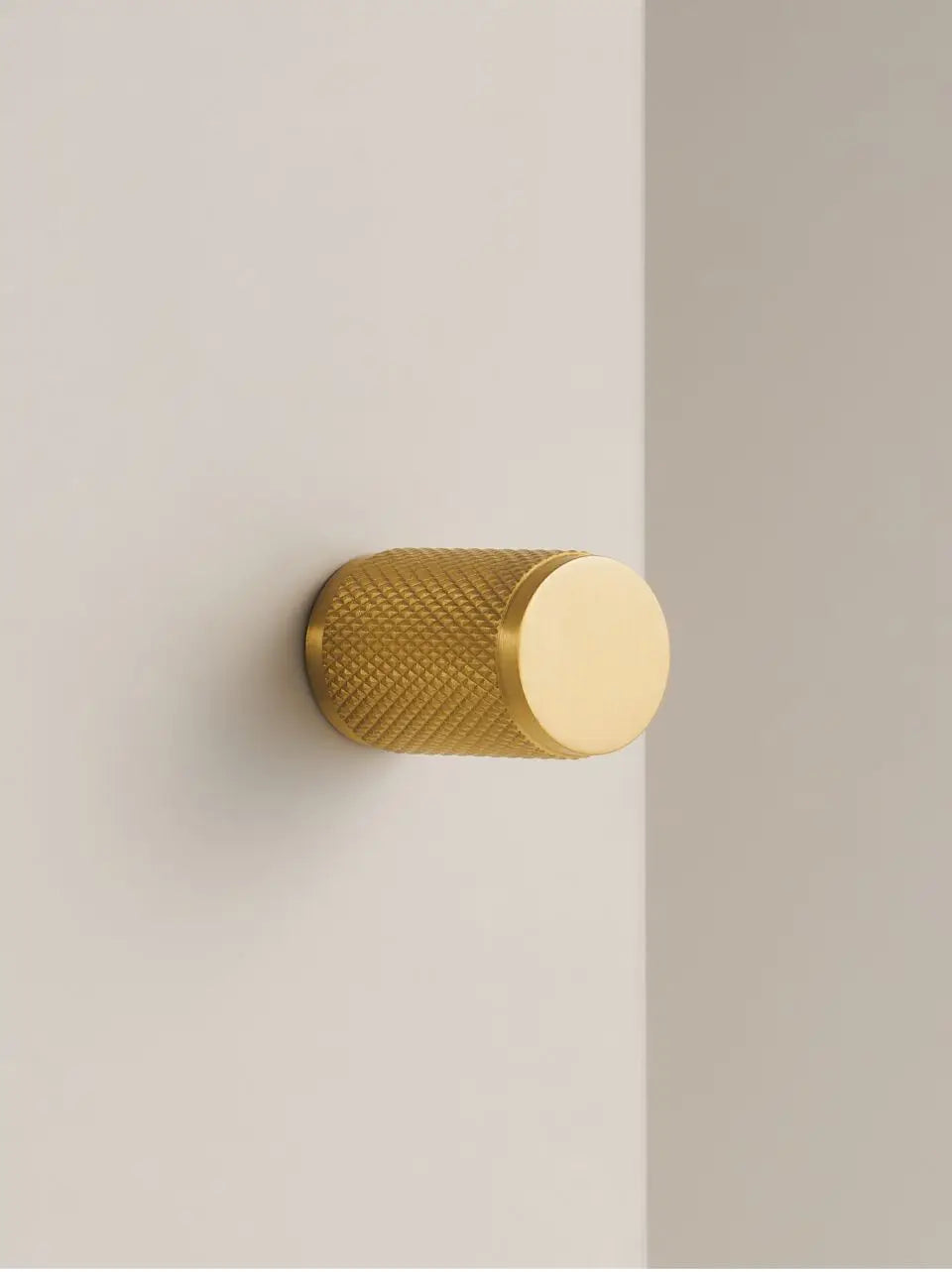 Gold cabinet brass cross knurled knob on a neutral background.