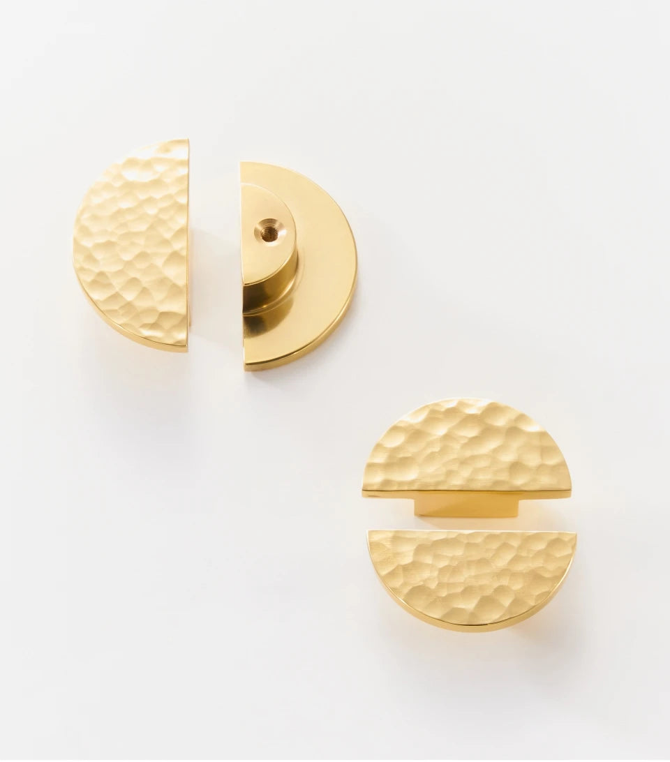 Four gold half circle hammered cabinet knobs on a white background.
