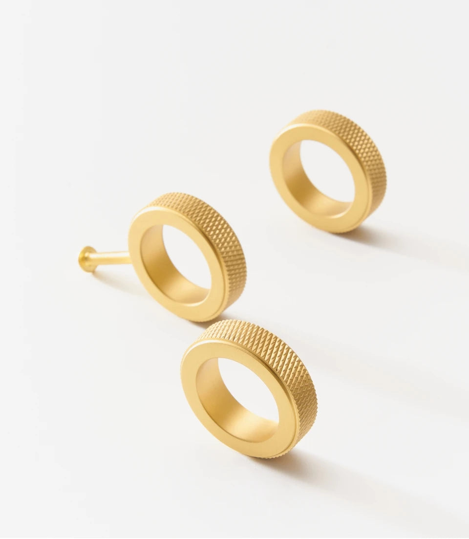 Gold knurled brass ring cabinet knobs on a white background.