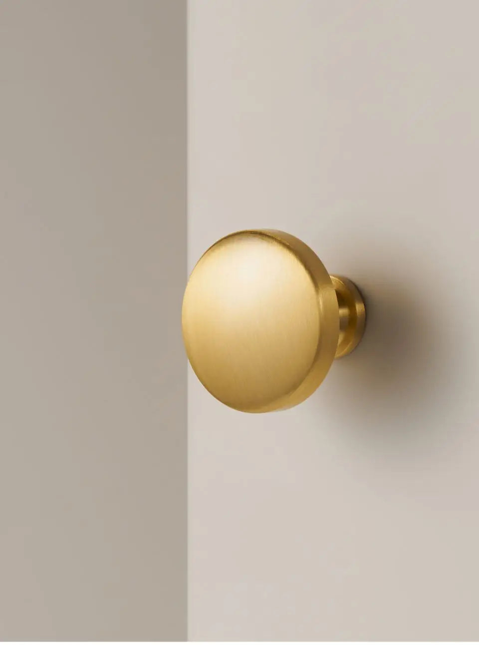 Gold solid brass cabinet door knob on a neutral background.