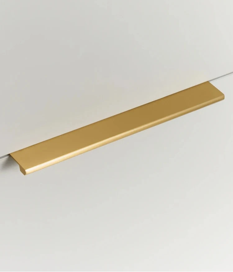 Long gold cabinet edge pull on a white cabinet door.