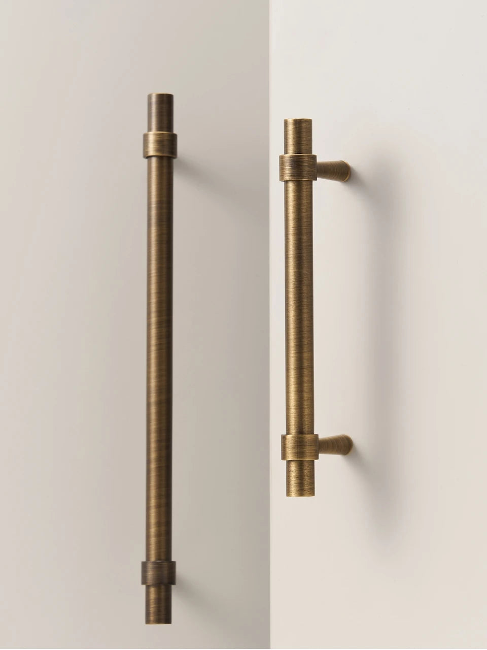 Pair of antique brass stepped ring door handles on a neutral background.